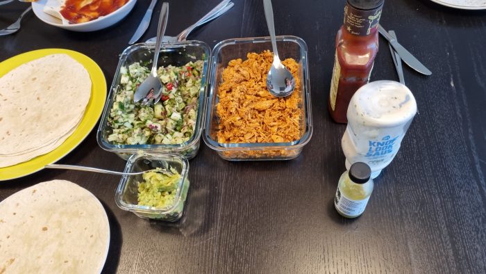 De tortilla's, pulled, chicken, salsa, avocado en sausjes op tafel
