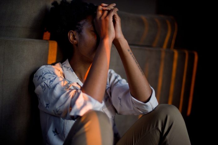 Vrouw die te veel prikkels heeft gekregen zit met haar handen op haar hoofd op de grond.