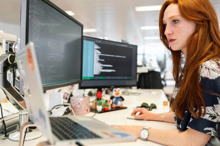 Vrouwelijke developer achter een computer met 2 schermen